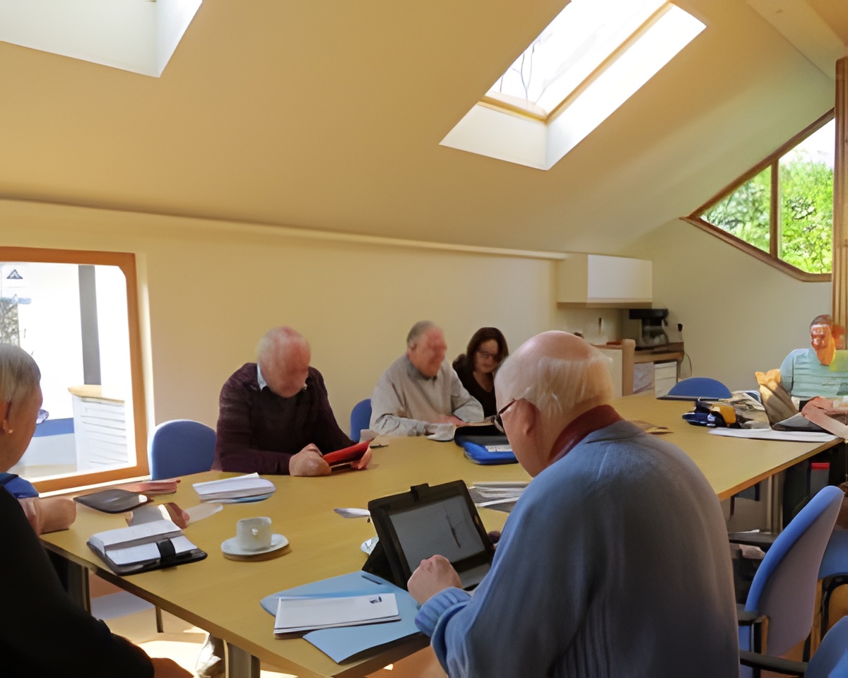 Members of the Internet Club gathered around a table with tablets and laptops, helping each other